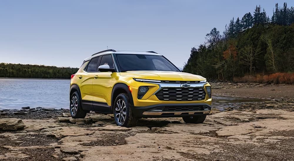 A yellow 2024 Chevy Trailblazer ACTIV is shown parked off-road near a lake.