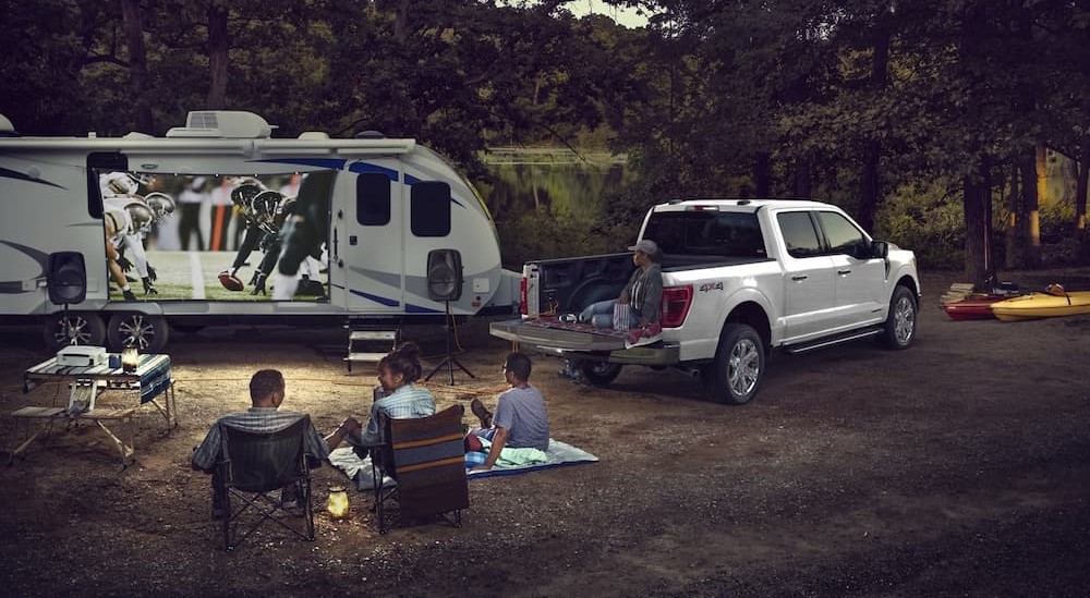 A white 2023 Ford F-150 is shown parked on a campsite.