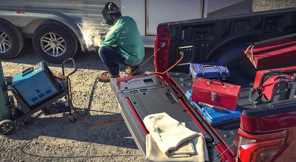 A person is working near a red 2023 Ford F-150.