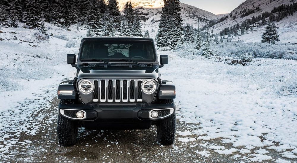 A popular Jeep Wrangler for sale, a black 2024 Jeep Wrangler, is shown parked on snow.