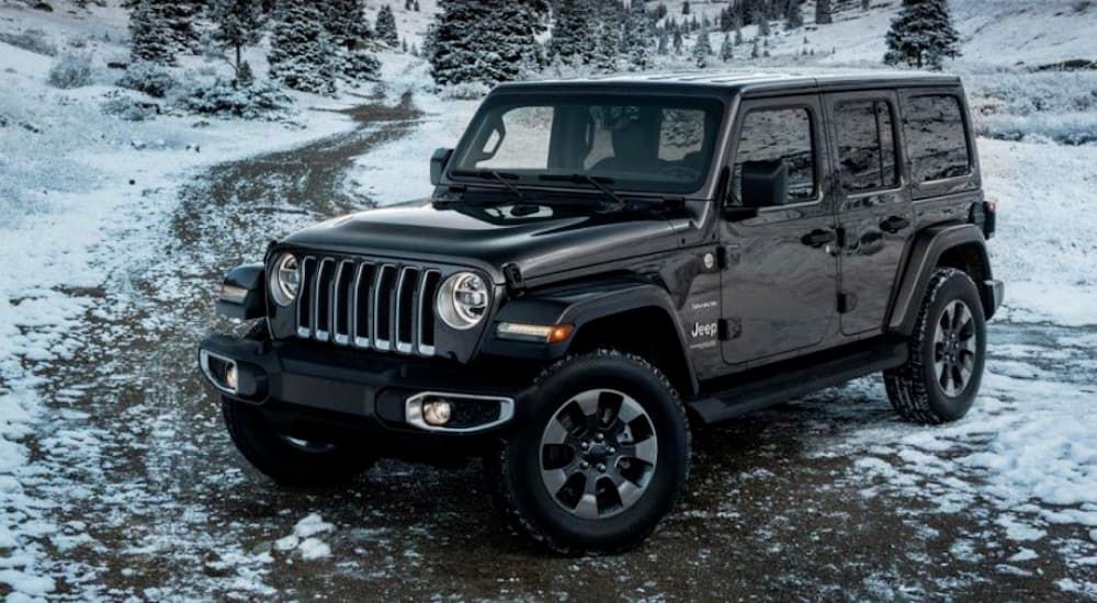 A black 2024 Jeep Wrangler Unlimited is shown parked on a snowy path.