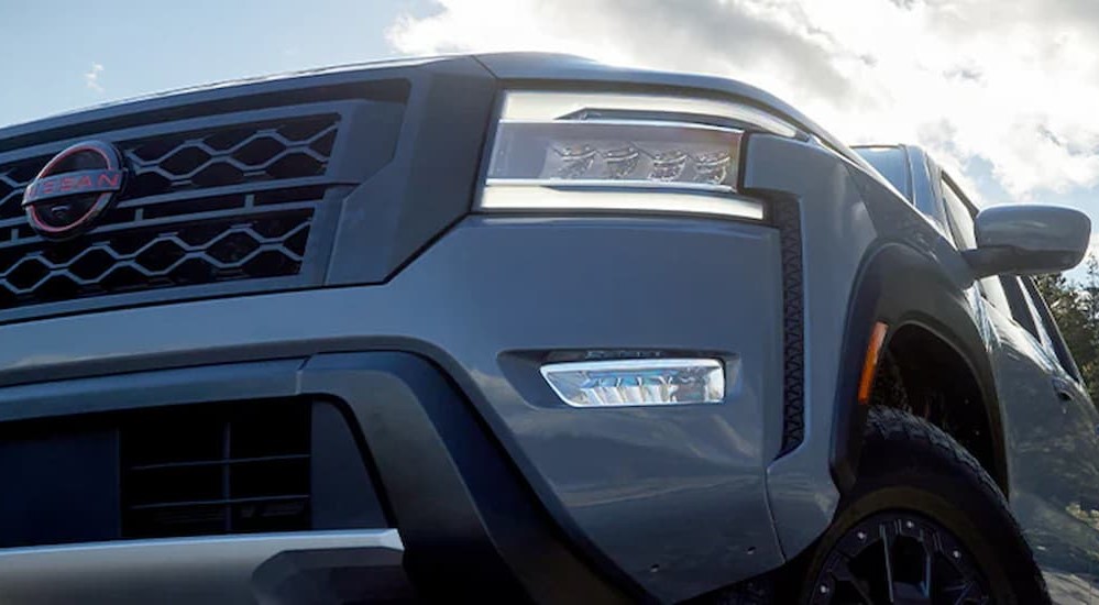 A close-up of the grille and headlight on a gray 2024 Nissan Frontier is shown.