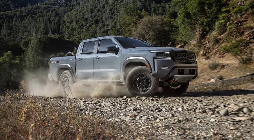 A gray 2024 Nissan Frontier Pro-4X is shown driving off-road.