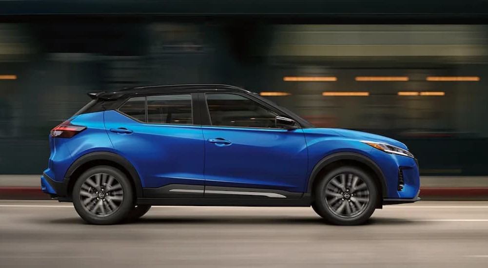 A blue 2024 Nissan Kicks is shown driving on a city street.