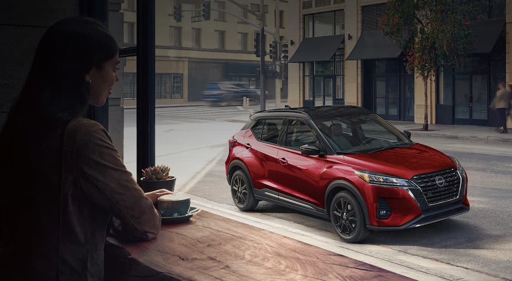 A red 2024 Nissan Kicks is shown parked near a sidewalk.