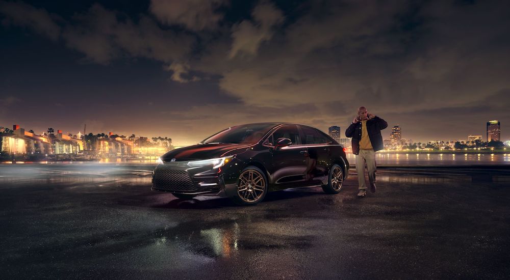 A black 2024 Toyota Corolla is shown parked near a city.