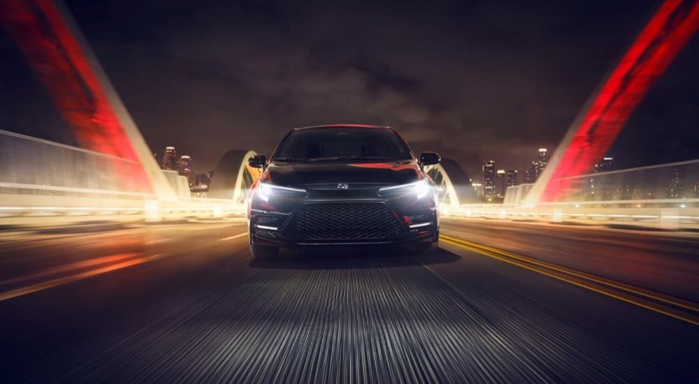 A black 2024 Toyota Corolla Nightshade is shown driving on a bridge.