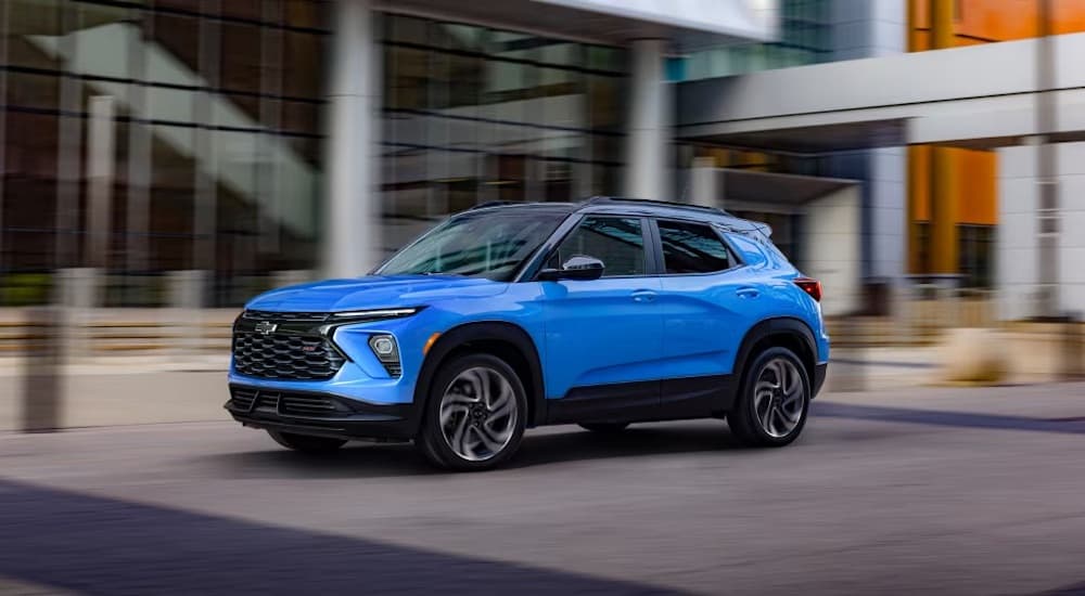 A blue 2024 Chevy Trailblazer RS is shown driving near a building.