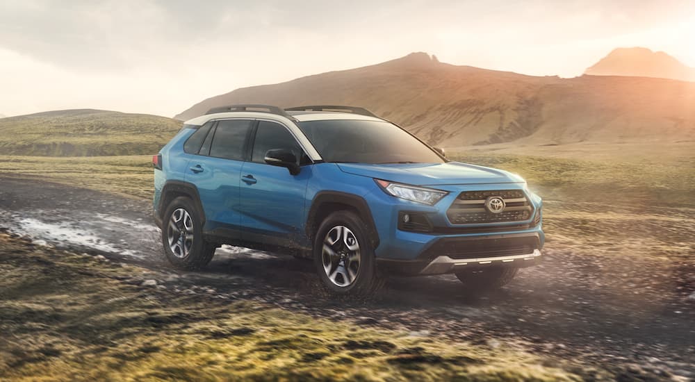 A popular used RAV4 for sale, a blue 2020 Toyota RAV4, is shown driving off-road.