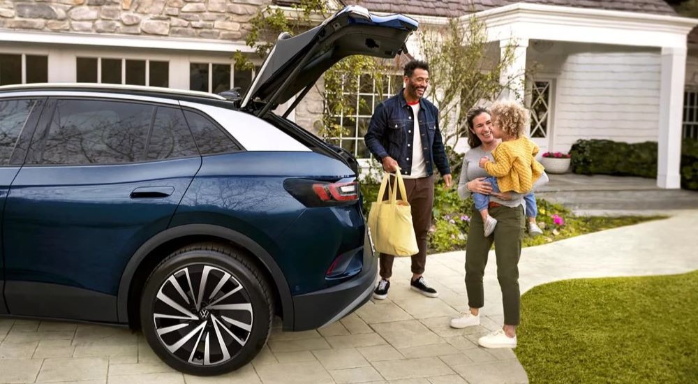 A family is shown unloading from the back of a dark blue 2023 Volkswagen ID.4 Pro S Plus.