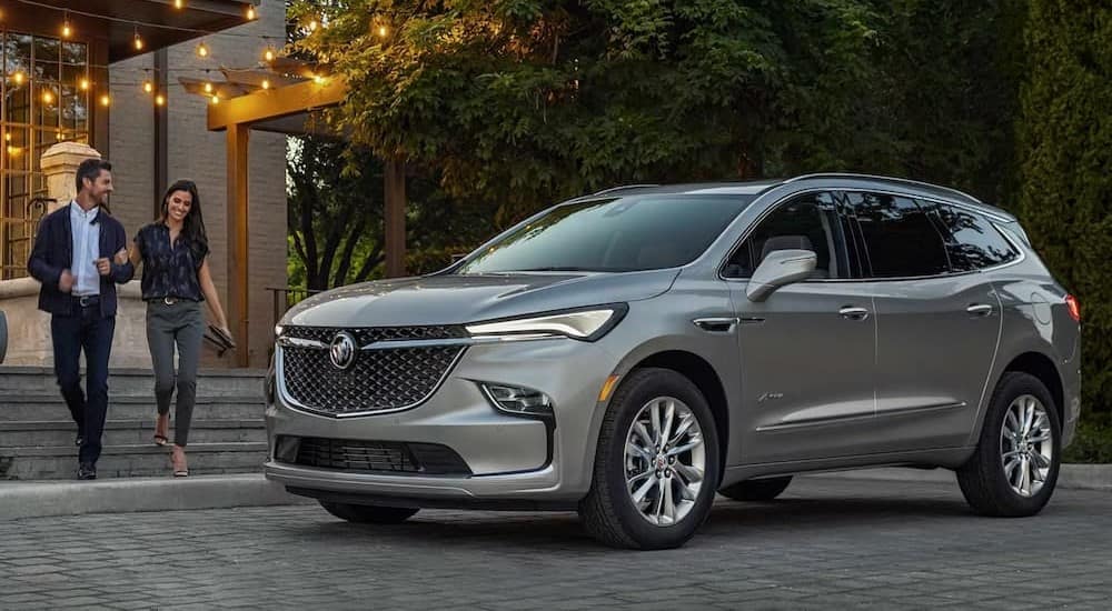 A grey 2024 Buick Enclave Avenir for sale is shown parked outside a building.