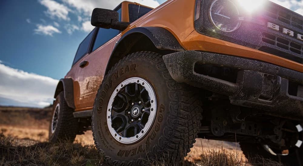 An orange 2024 Ford Bronco Heritage is shown parked off-road.