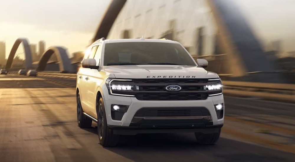 A white 2024 Ford Expedition is shown driving on a bridge.