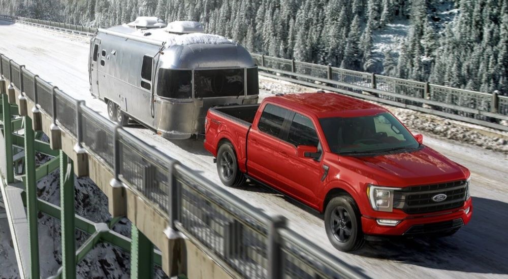 A red 2024 Ford F-150 XL is shown towing a trailer over a bridge.