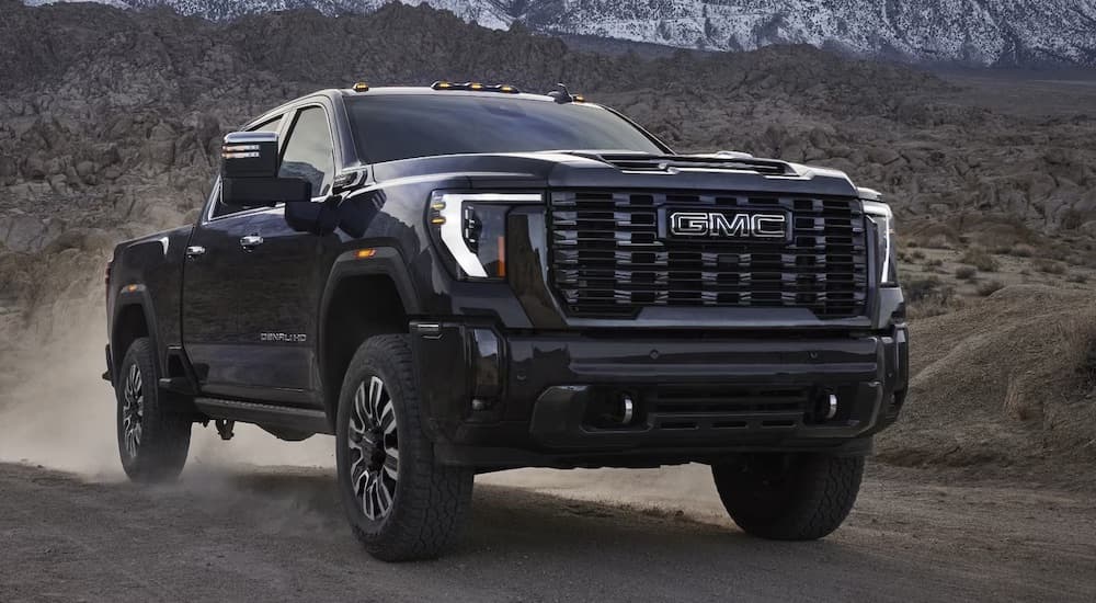 A black 2024 GMC Sierra 2500 HD is shown driving off-road.