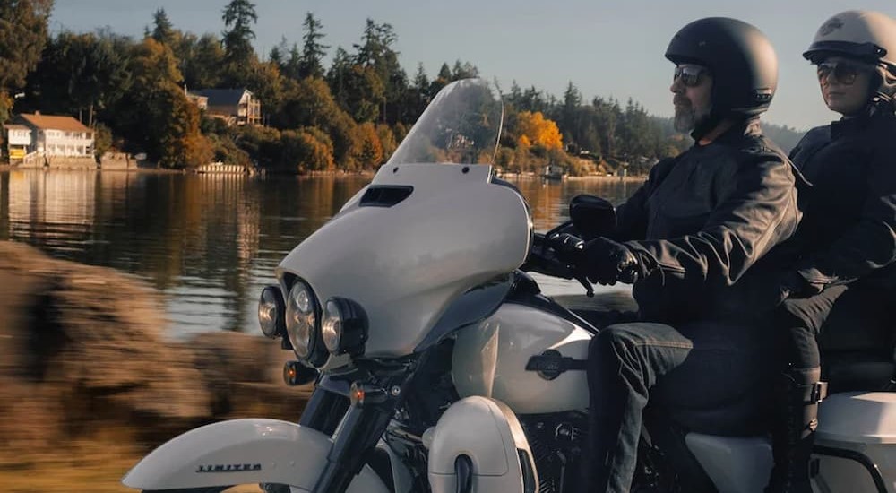 A white 2024 Harley-Davidson Ultra Limited for sale is shown riding by a lake.