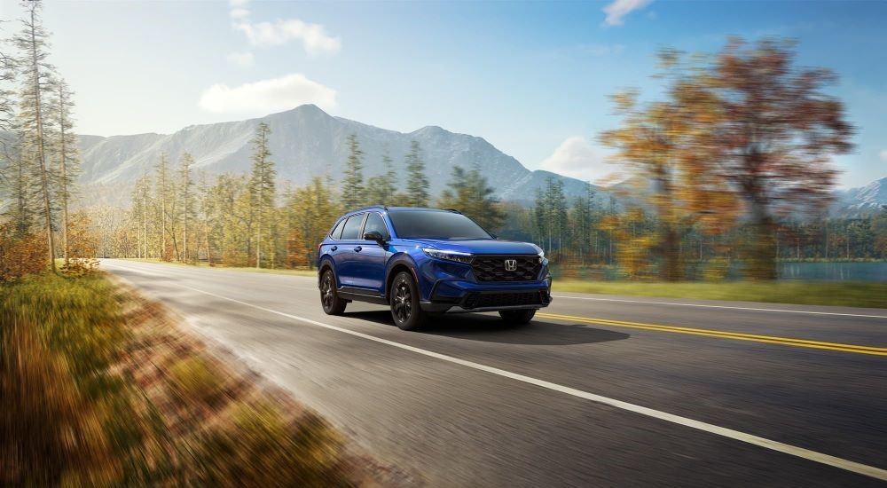 A blue 2024 Honda CR-V for sale is shown driving.