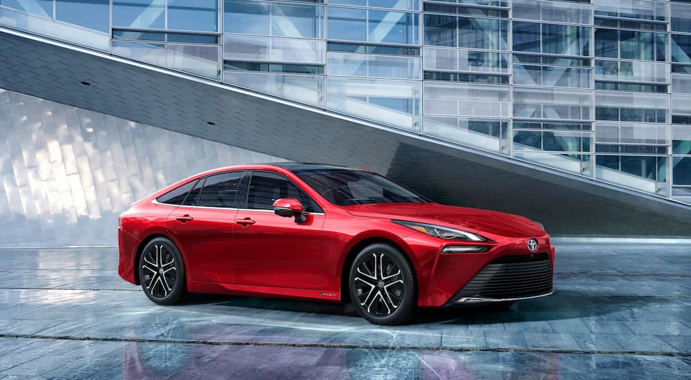 A red 2024 Toyota Mirai Limited parked in a modern showroom at a Toyota dealer.