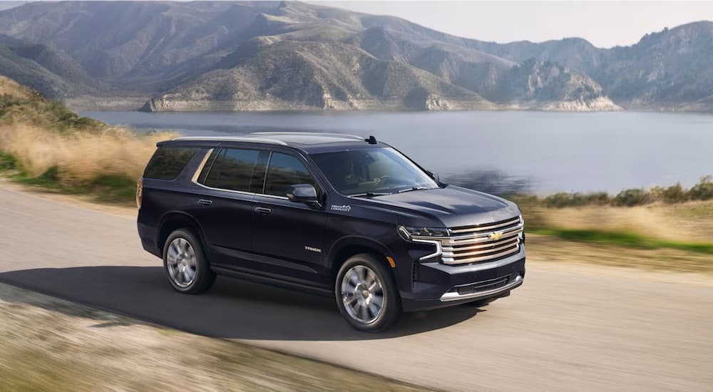 A black 2024 Chevy Tahoe High Country is shown driving.