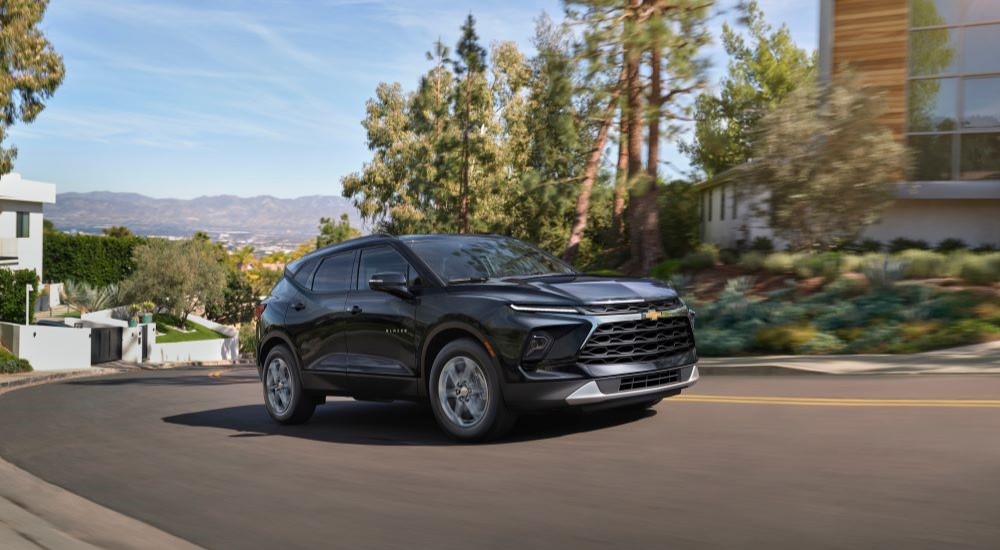 A black 2024 Chevy Blazer for sale driving through a residential neighborhood.