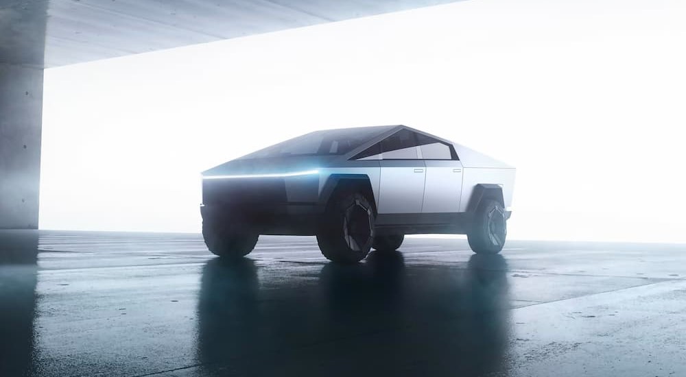 A silver Tesla Cybertruck is shown parked on a sunny day.