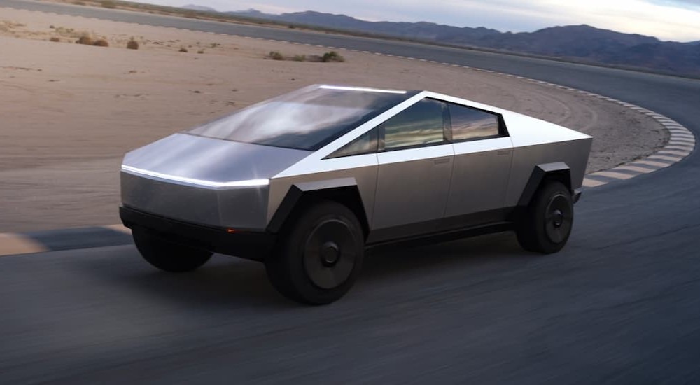 A silver Tesla Cybertruck is shown driving on a racetrack.