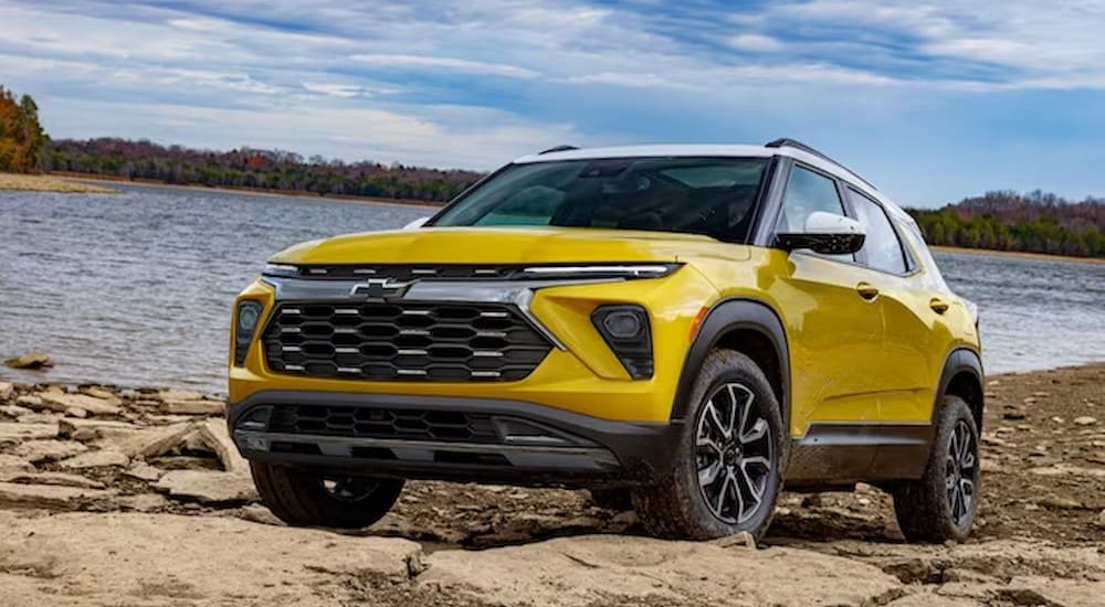 A yellow 2024 Chevy Trailblazer for sale is shown parked near an ocean.