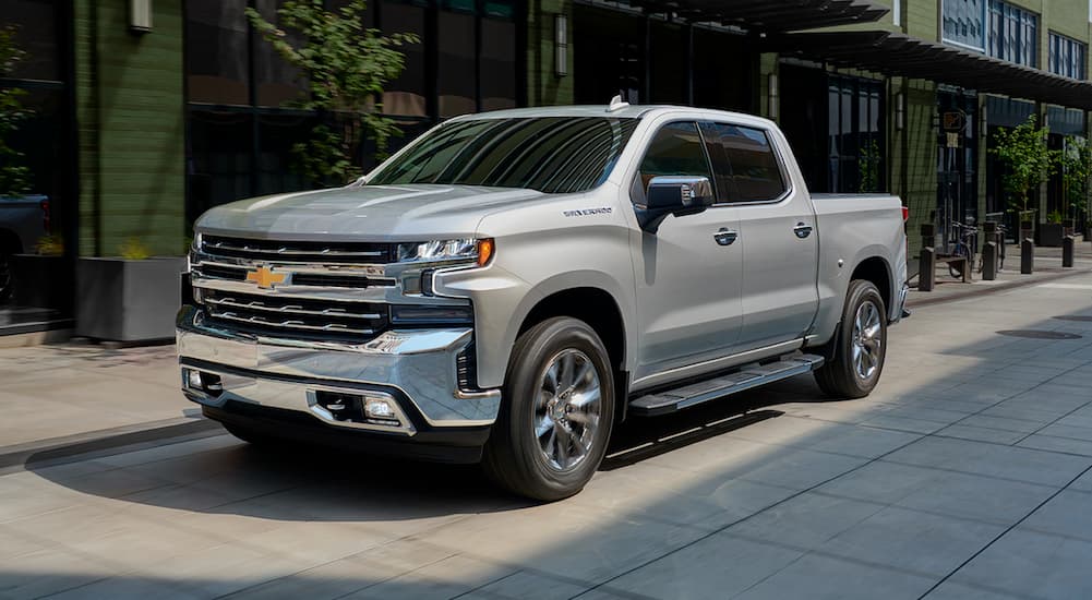 A popular used Chevy Silverado for sale, a silver 2019 Chevy Silverado, is shown parked on a city street.