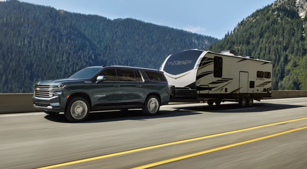 One of many popular used SUVs for sale, a 2021 Chevy Suburban High Country, is shown towing a trailer.