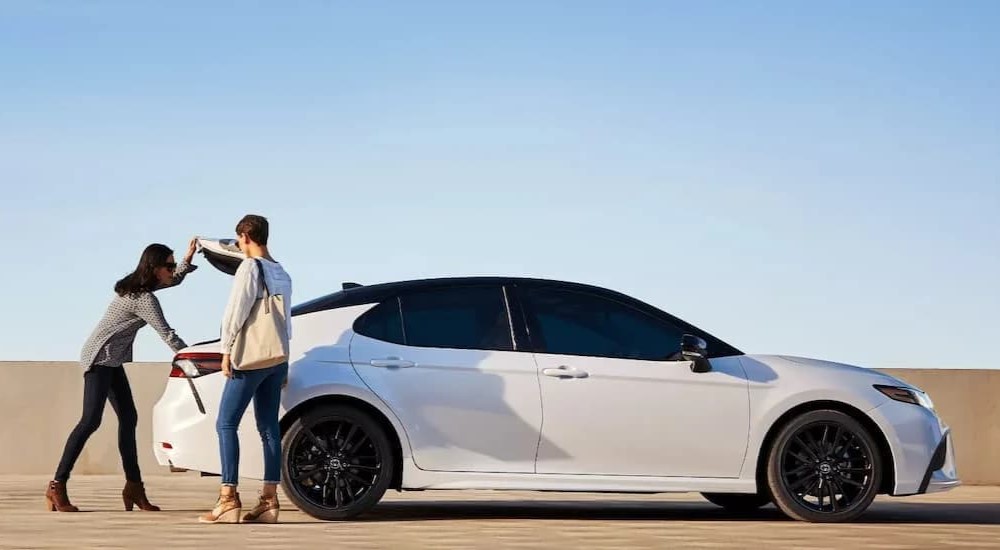 A white 2022 Toyota Camry XSE is shown parked near two people after visiting a used Toyota dealer.