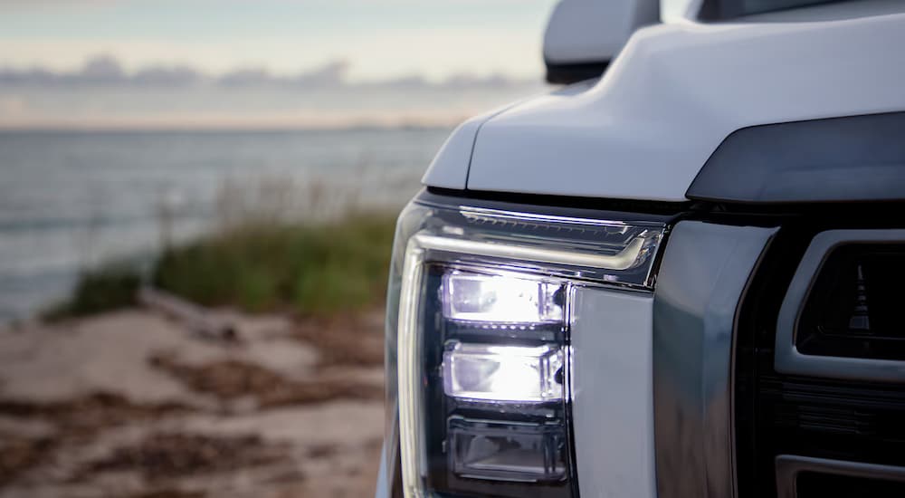 A closeup of the headlight on a white 2024 GMC Yukon AT4.