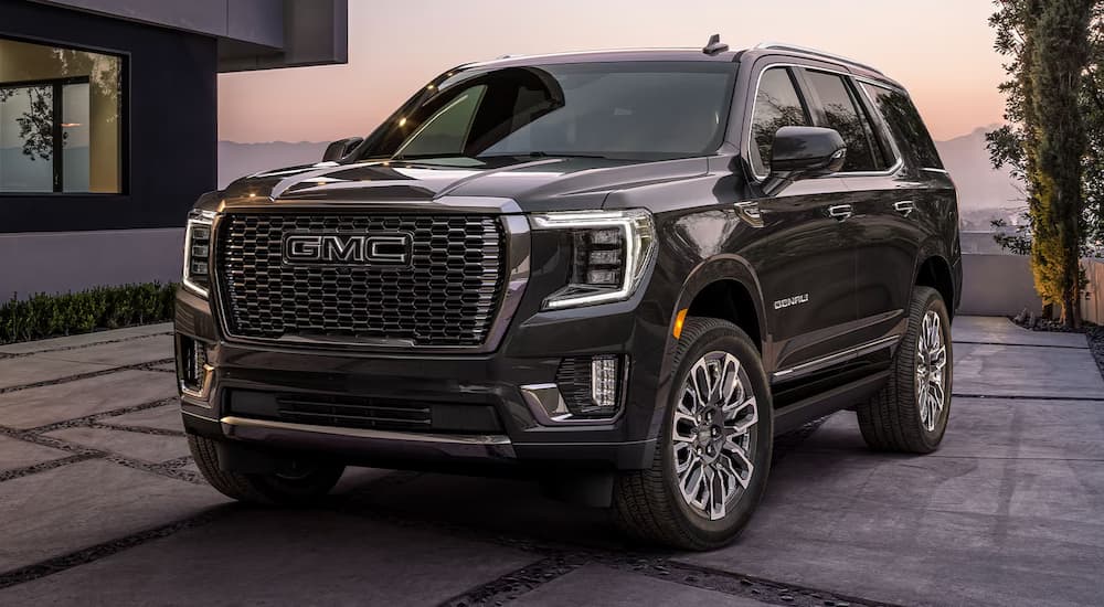 A black 2024 GMC Yukon Denali parked outside a home at dusk.