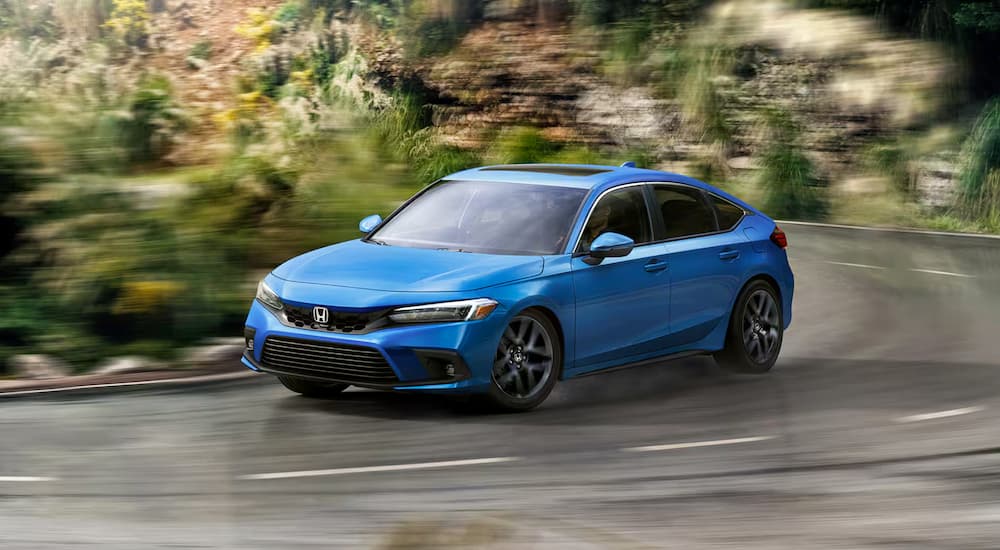 A blue 2024 Honda Civic Hatchback is shown driving.