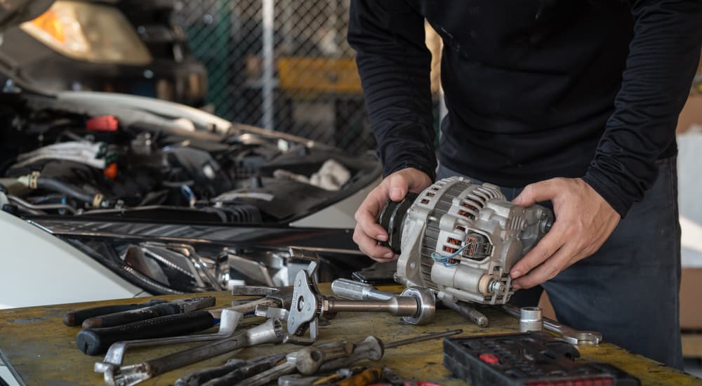 A person is shown performing an alternator replacement in a garage.