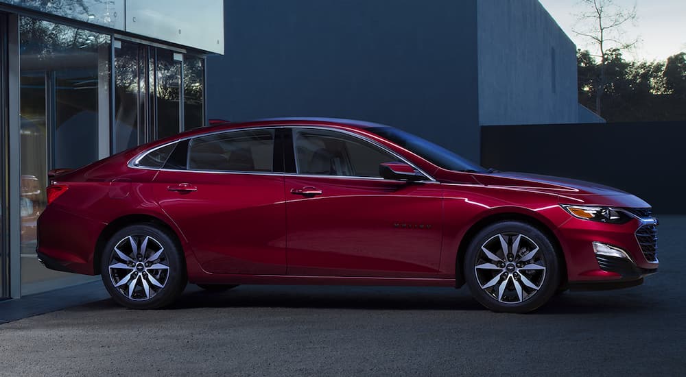 A red 2024 Chevy Malibu is shown parked outside a building after visiting a dealer with a Chevy Malibu for sale.