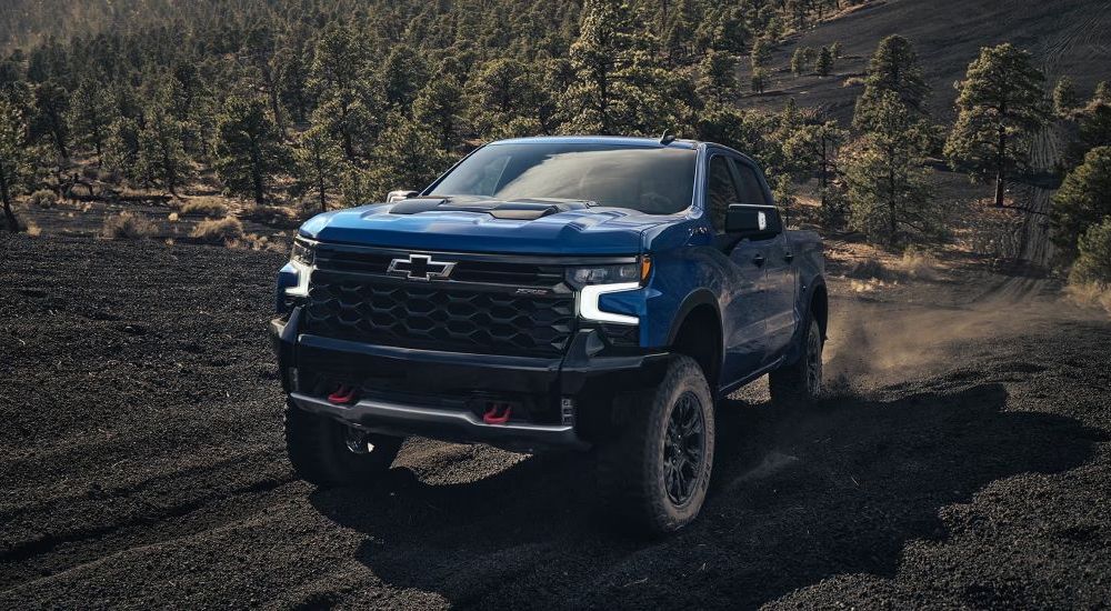 A blue 2024 Chevy Silverado 1500 ZR2 is shown driving off-road.