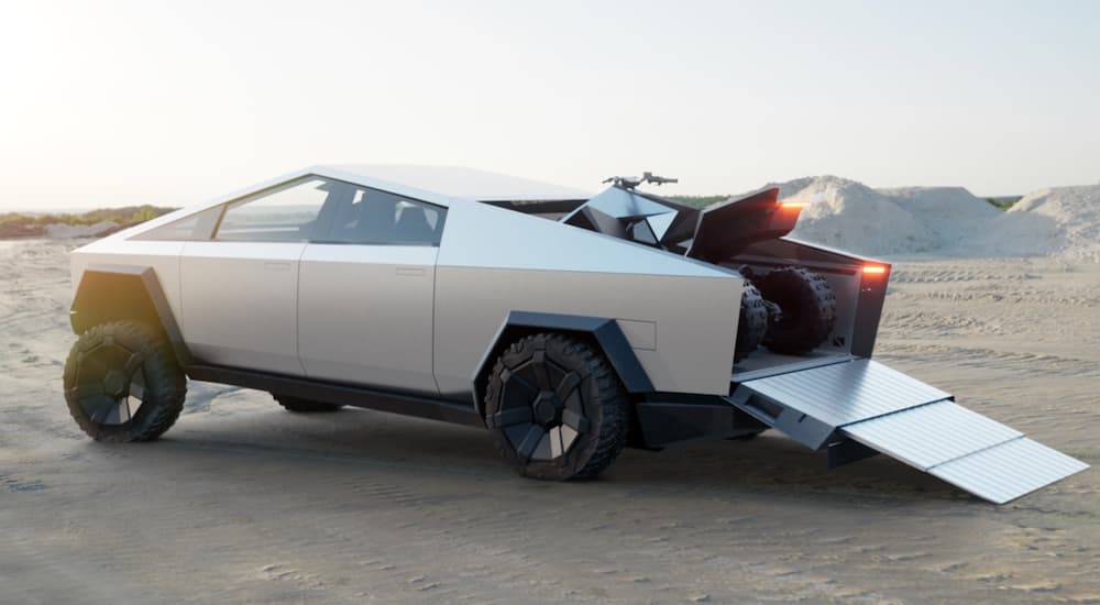 A grey 2023 Tesla Cybertruck is shown parked off-road with its trunk ramp down.