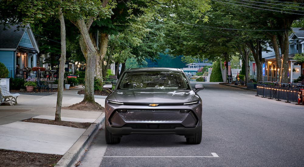 A grey 2024 Chevy Equinox EV 1LT is shown from the front parked on a city street.