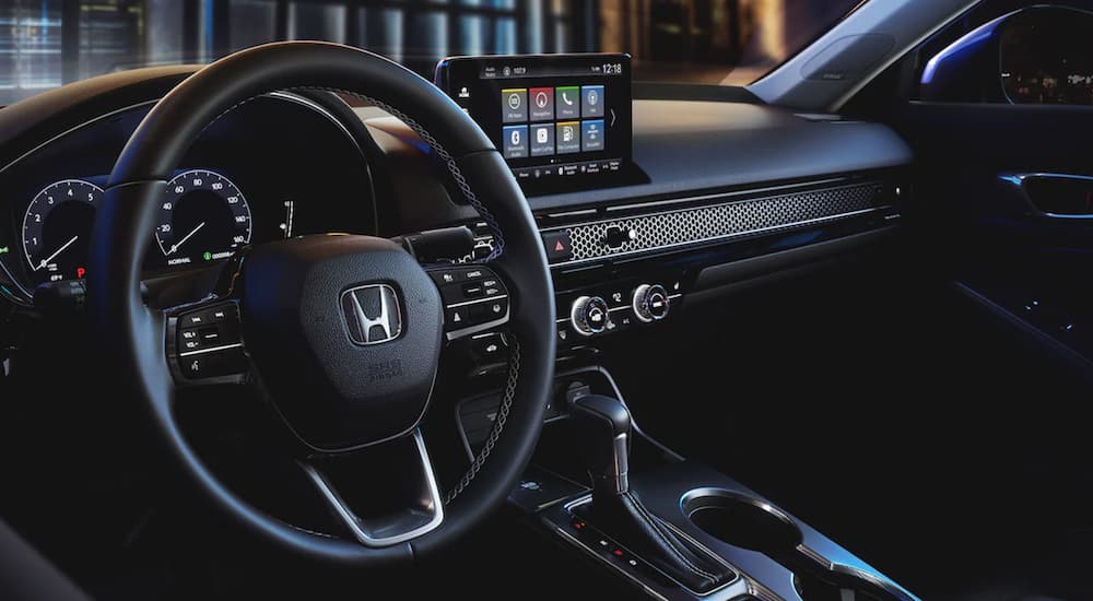 The black steering wheel and infotainment screen in a 2024 Honda Civic Touring.