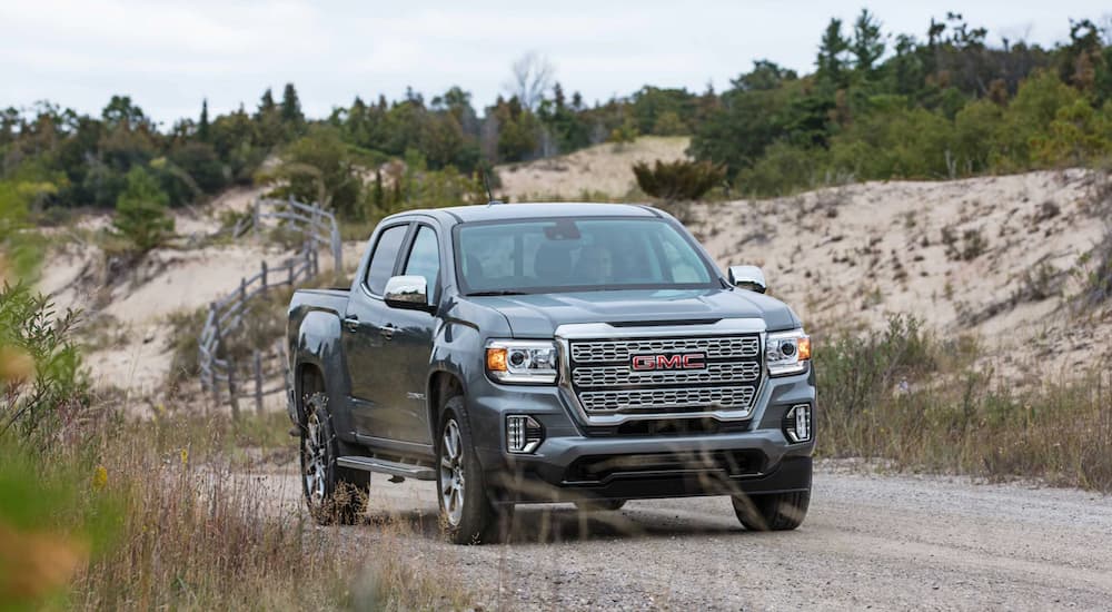 A gray 2021 GMC Canyon is shown driving on a dirt road.