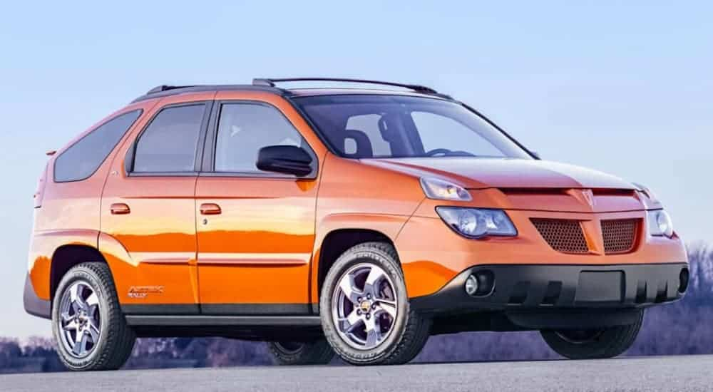 An orange 2004 Pontiac Aztek is shown parked off-road.