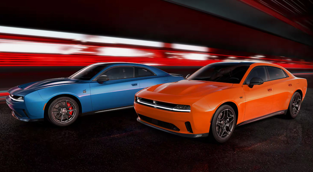 An orange 2024 Dodge Charger Daytona R/T and a blue 2024 Dodge Charger Daytona Scat Pack parked under dramatic lighting.