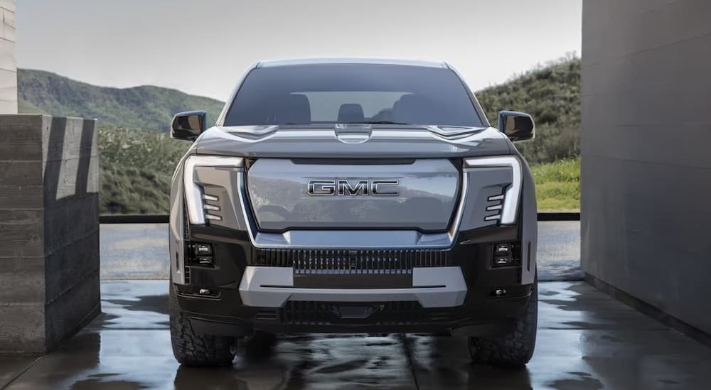 Front view of a grey 2024 GMC Sierra EV Denali Edition 1 parked on wet pavement.