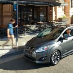 A grey 2017 Ford C-Max Energi is parked on the side of a city street.