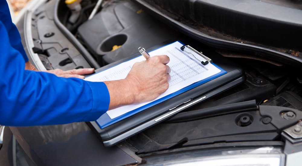 A mechanic is shown writing on a clipboard.
