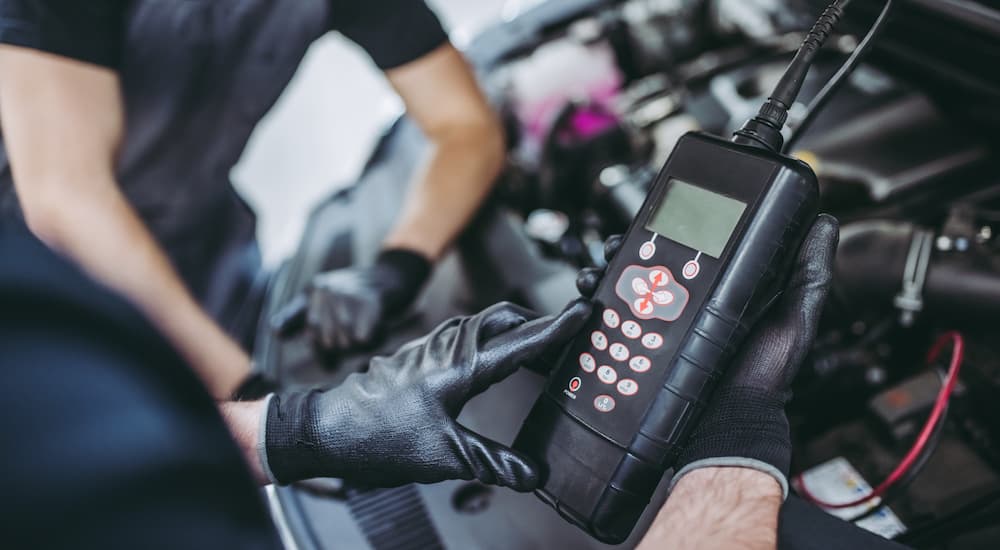 A mechanic is shown using a multimeter on a car.