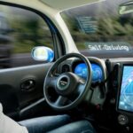 A person is shown sitting in a self-driving car.