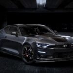 A black 2024 Chevy Camaro ZL1 is shown parked in a dark room.