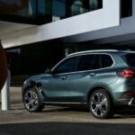 A green 2025 BMW X5 is shown charging near a person.