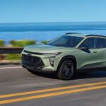 A green 2025 Chevy Trax ACTIV driving along a coastal road.